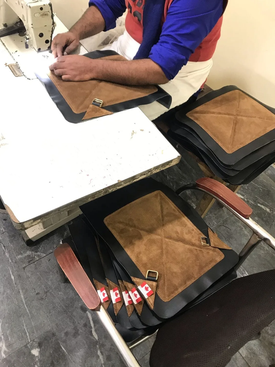 A craftsman stitching a production batch of leather panels at a sewing machine