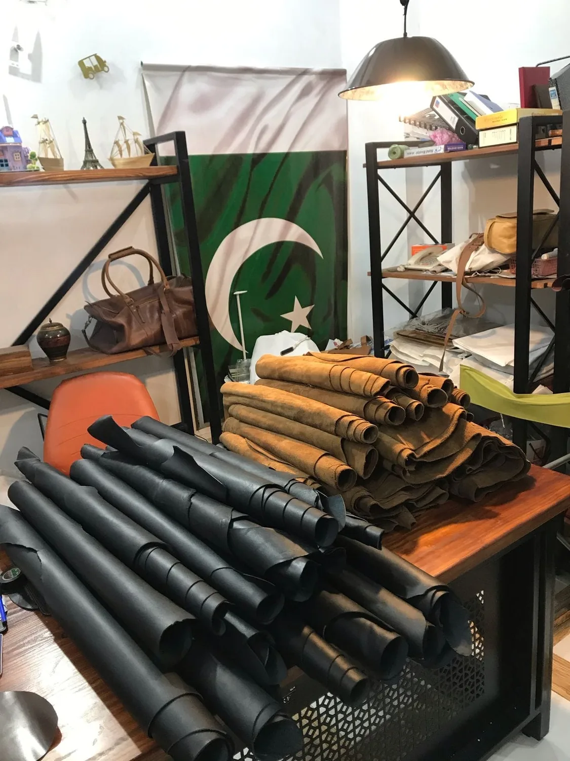 Rolled hides of black and tan leather stacked in the Bin Salman workshop